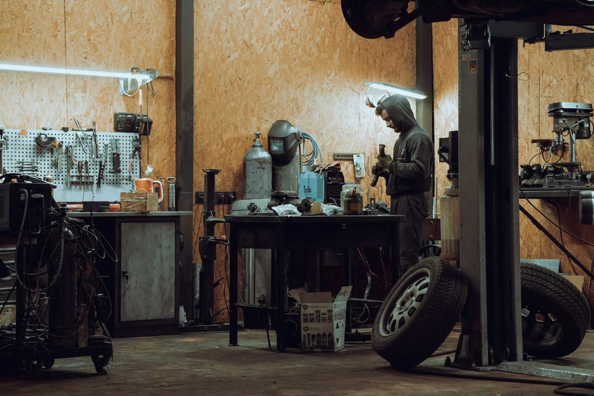 Mechanic reviewing a job sheet beside a car on a hoist in a workshop